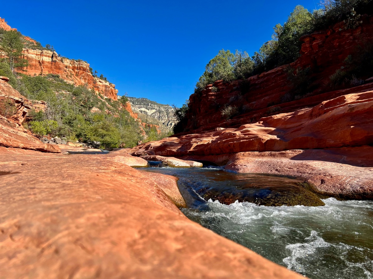 A rushing creek flows through red cliffs in Sedona, Arizona