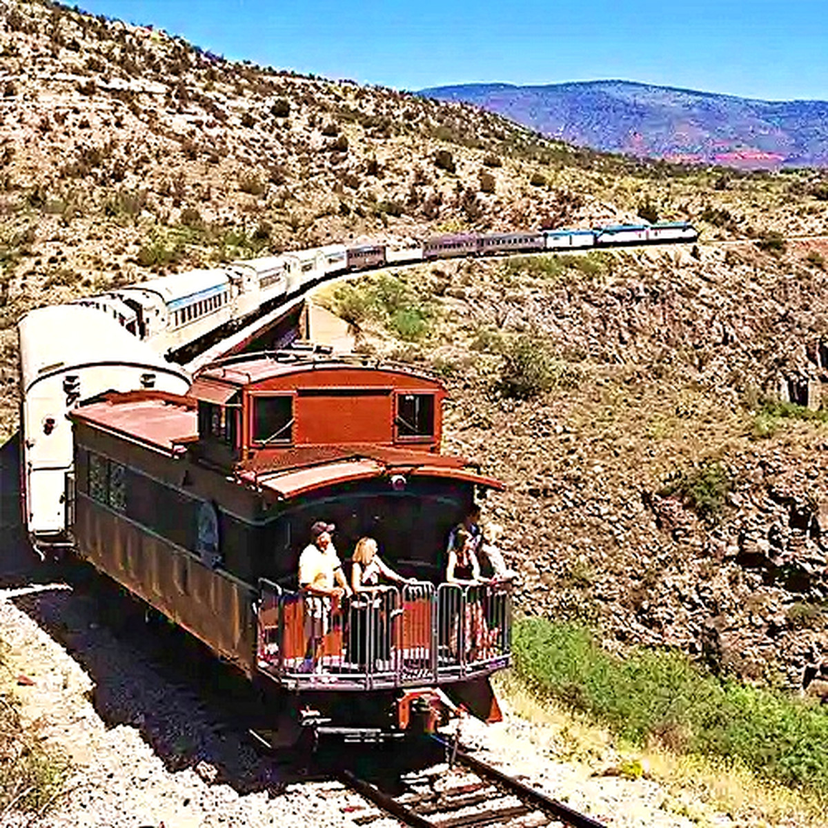 People enjoy the view from the red caboose of the Verde Canyon Railroad